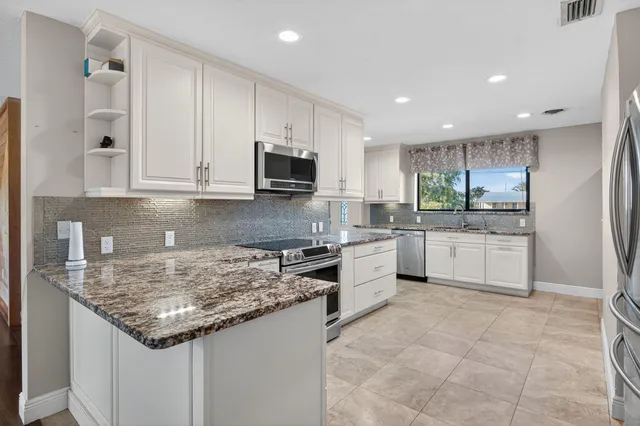 a kitchen with a stove a sink a microwave a refrigerator and cabinets