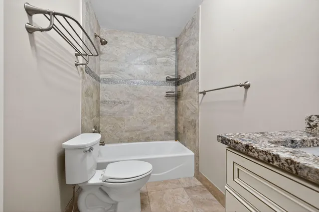 a bathroom with a granite countertop toilet a sink and a shower