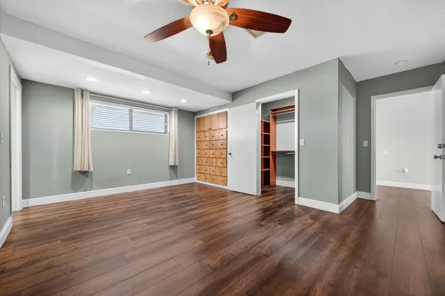 a view of an empty room with window and wooden floor
