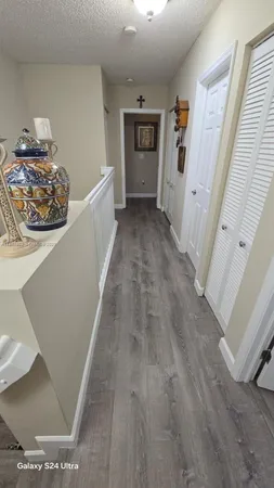 a view of a hallway to a livingroom with wooden floor and furniture