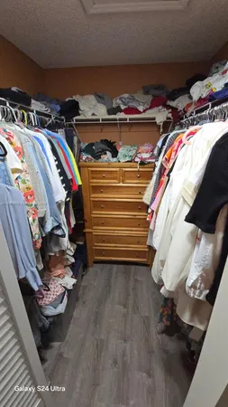 a view of walk in closet with clothes and shoes