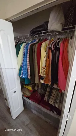 a view of walk in closet with clothes and shoes