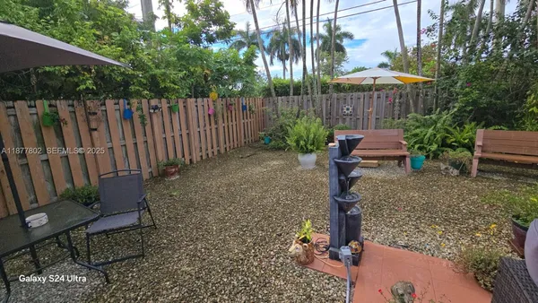 a view of a backyard with chairs potted plants and wooden fence