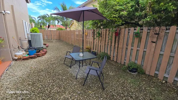 a view of backyard with table and chairs under an umbrella
