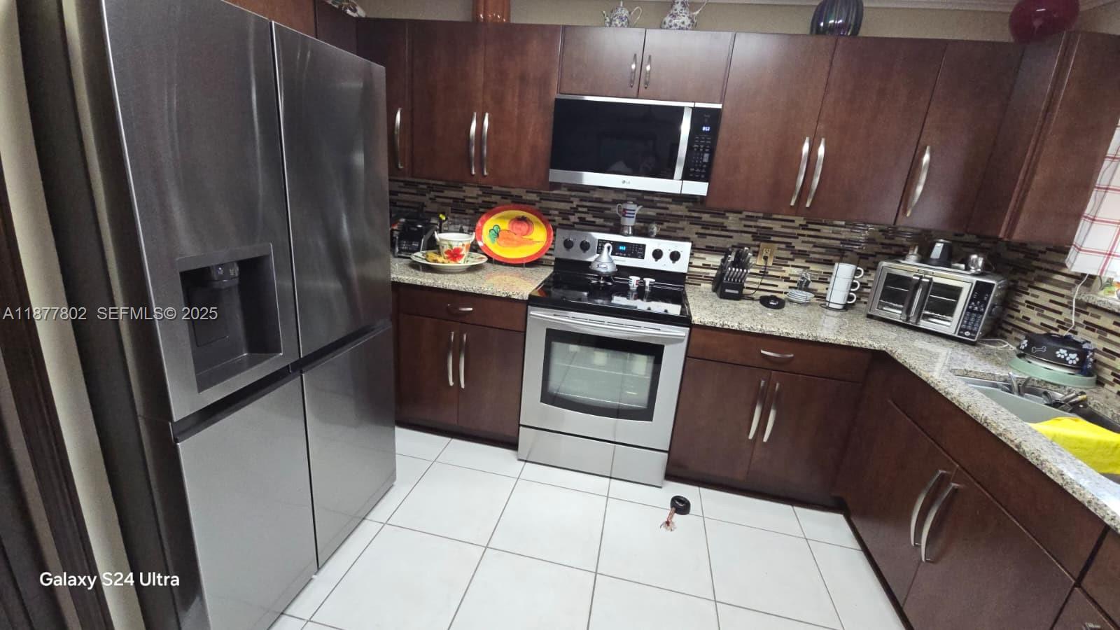 15436 Southwest 151st Terrace Miami, FL 33196 - Photo 7 of 50 a kitchen with granite countertop a stove top oven microwave and sink