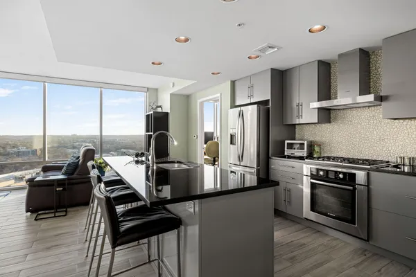 a kitchen with stainless steel appliances granite countertop a stove top oven a sink dishwasher a refrigerator and white cabinets with wooden floor