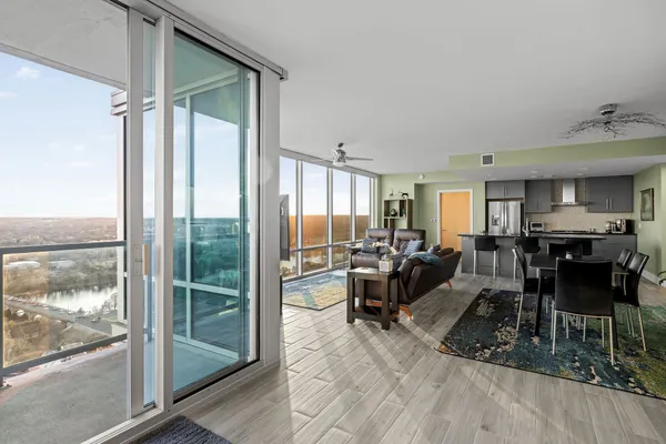 a living room with furniture a large window and wooden floor