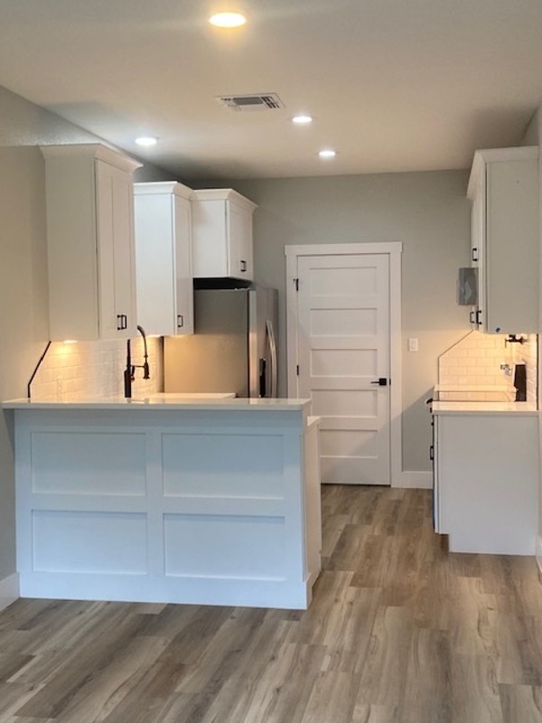 116 Field Street Luling, TX 78648 - Photo 29 of 33 A contemporary kitchen features sleek white cabinetry and durable wood-look flooring.