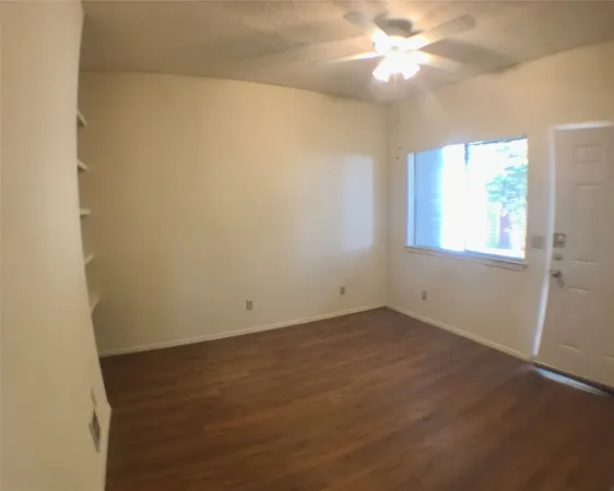 an empty room with a window and a fan