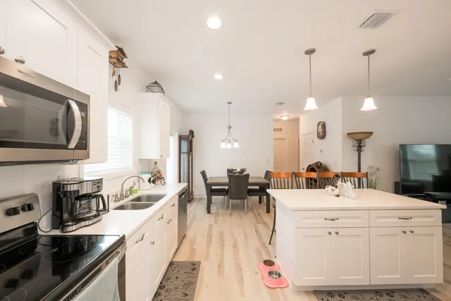 a large kitchen with kitchen island white cabinets and stainless steel appliances