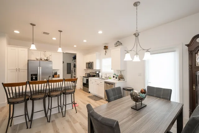 a view of a dining room and livingroom with furniture wooden floor a chandelier