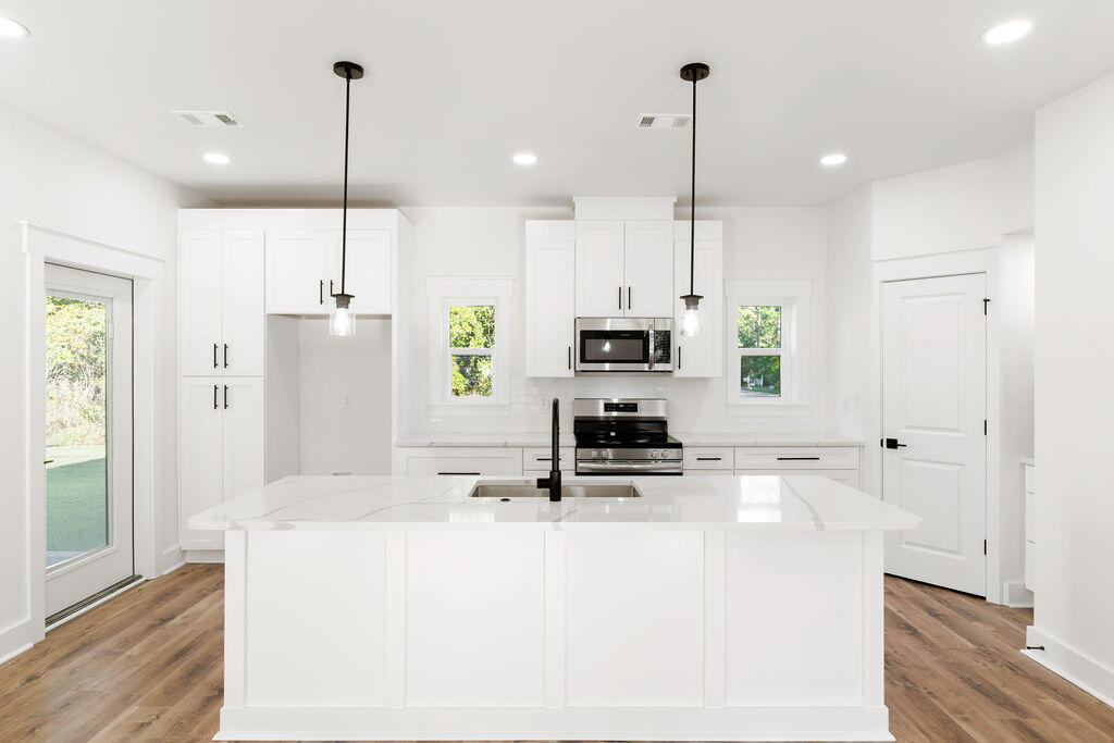 32 22nd Street Santa Rosa Beach, FL 32459 - Photo 6 of 26 a kitchen with stainless steel appliances kitchen island granite countertop a refrigerator a stove and white cabinets with wooden floor