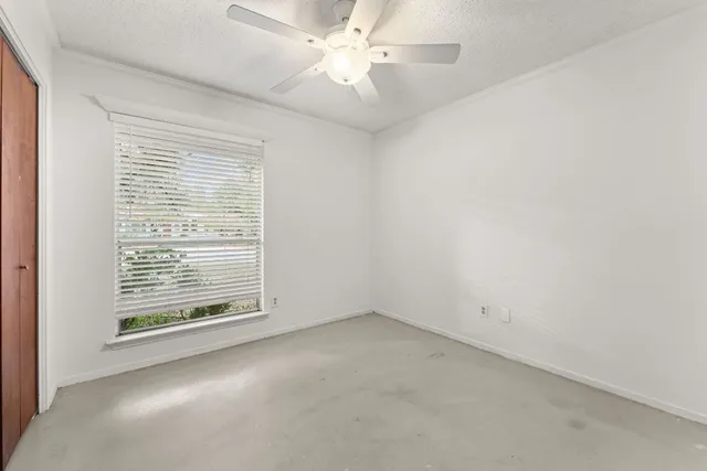 an empty room with a window and a fan