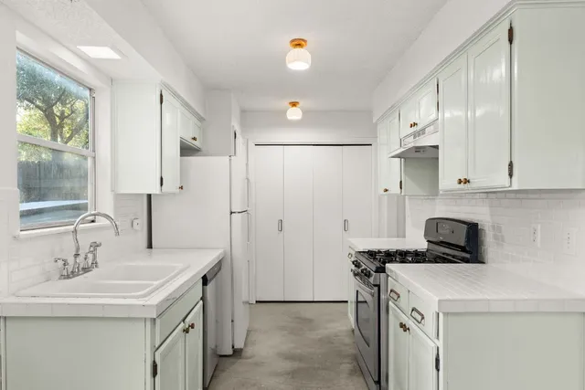 a kitchen that has a sink a stove and a refrigerator