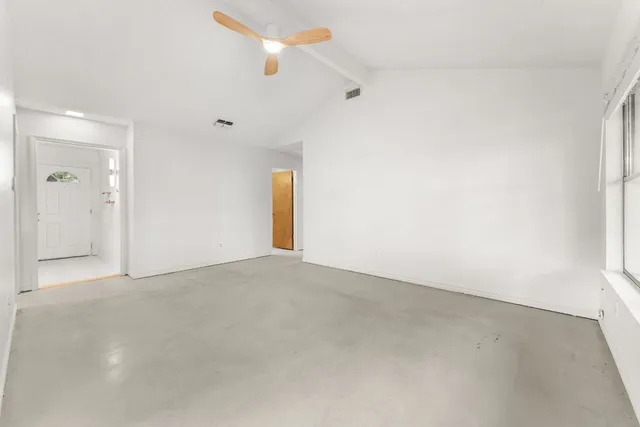 an empty room with a fan & a window