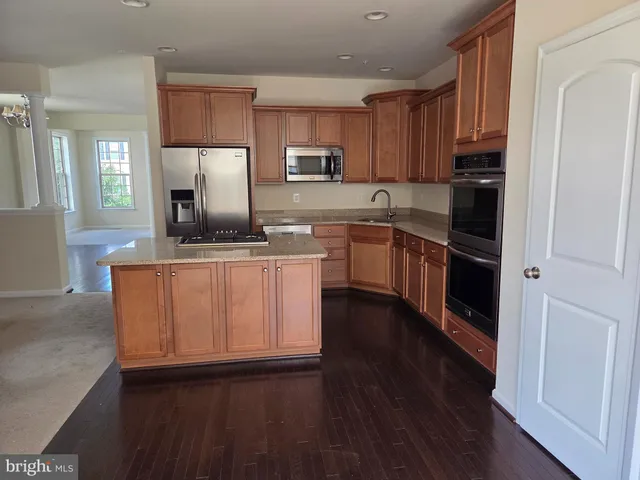 a kitchen with kitchen island granite countertop stainless steel appliances and wooden cabinets