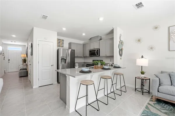 a kitchen with stainless steel appliances a refrigerator a stove a sink a dining table and chairs