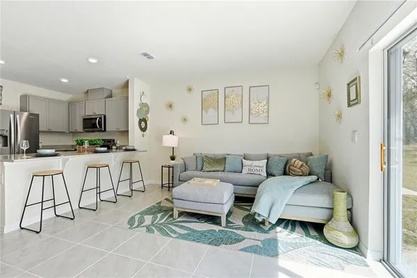 a living room with furniture a kitchen view and a refrigerator