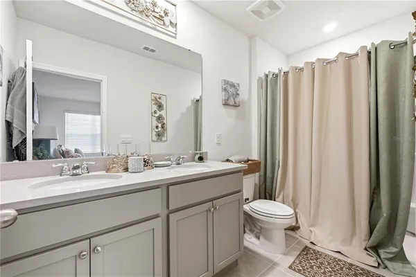 a bathroom with double vanity sink a toilet a mirror and shower