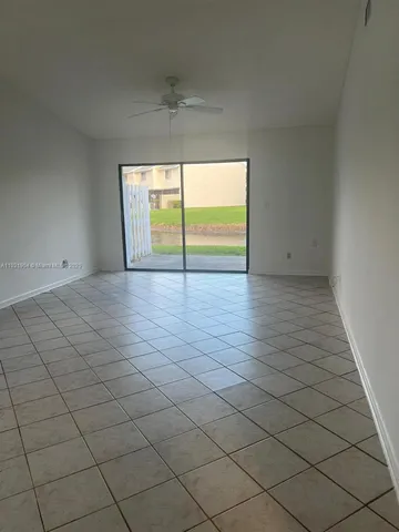 an empty room with windows and view of kitchen