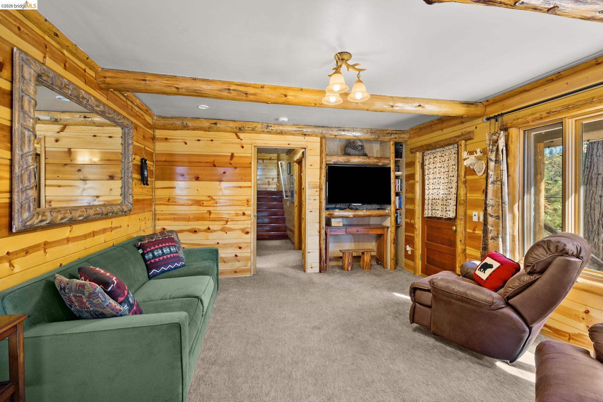 25972 Long Barn Road Long Barn, CA 95335 - Photo 12 of 36 Wood-paneled walls with exposed log beams throughout, built in shelves and TV and lots of windows for capturing natural light.