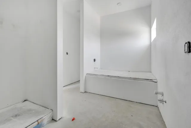 a view of a hallway with wooden floor and a bathroom