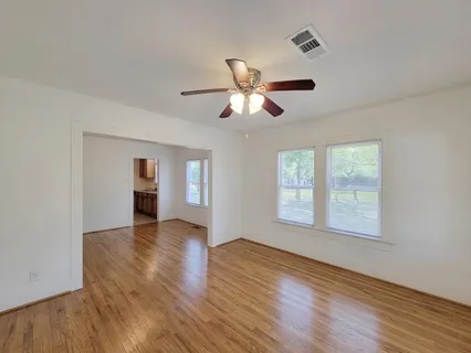 a view of an empty room with a window and wooden floor