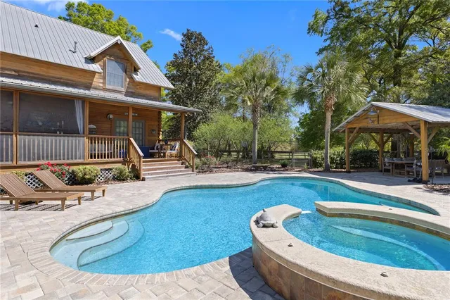 a view of a dining room with furniture a chandelier and large windows