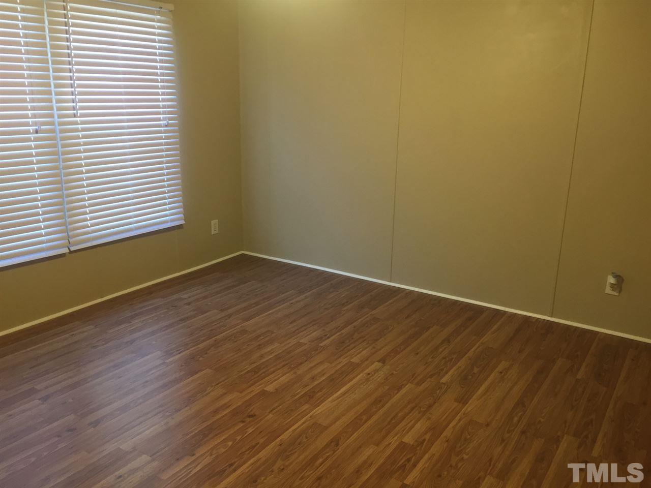 1313 Yakimas Road Raleigh, NC 27603 - Photo 3 of 9 an empty room with wooden floor and windows