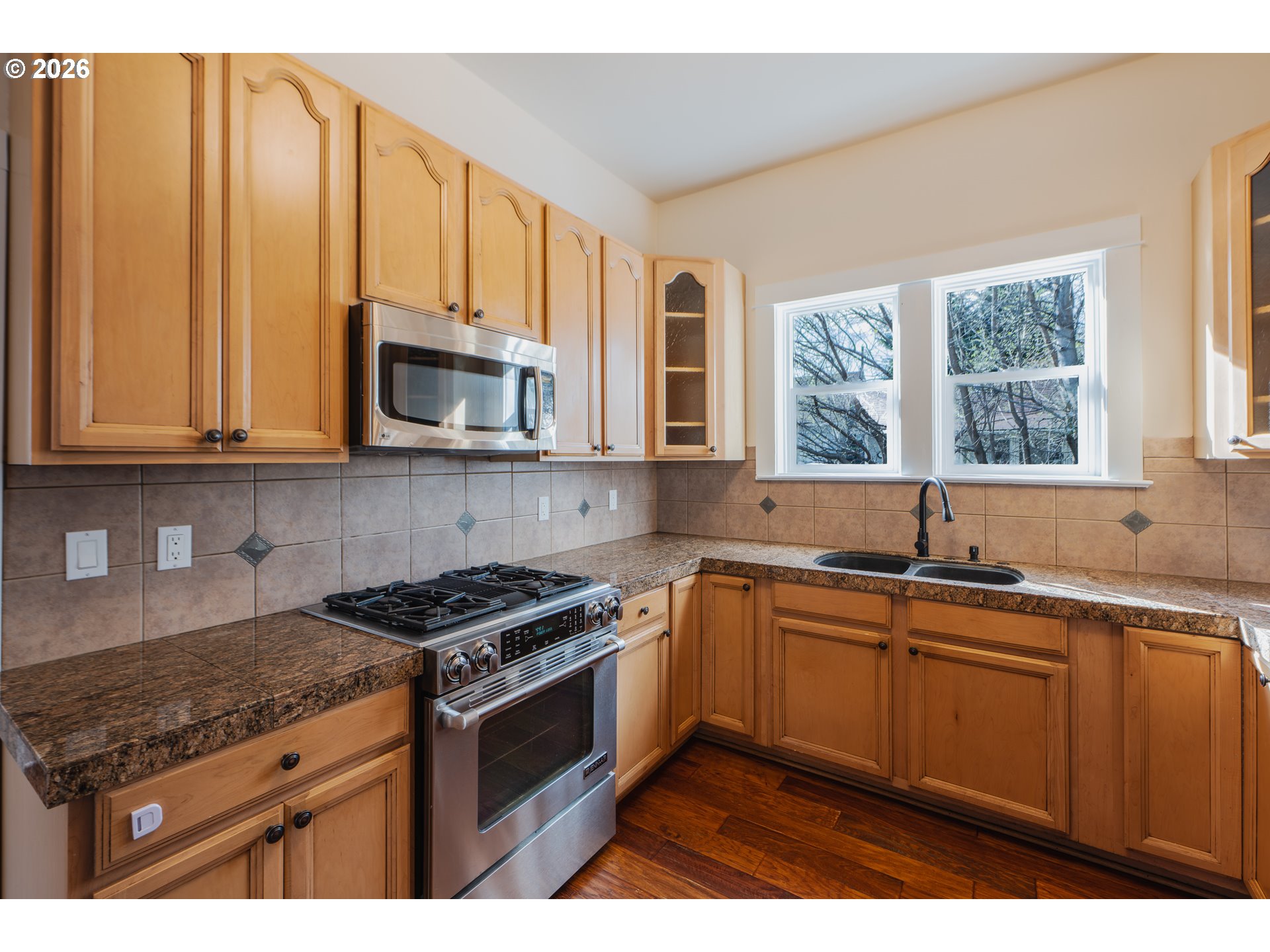 110 West 8th Street The Dalles, OR 97058 - Photo 11 of 43 a kitchen with stainless steel appliances granite countertop a sink a stove a microwave cabinets and a window
