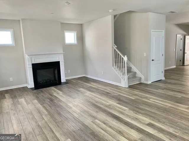 a view of an empty room with wooden floor fireplace and a window