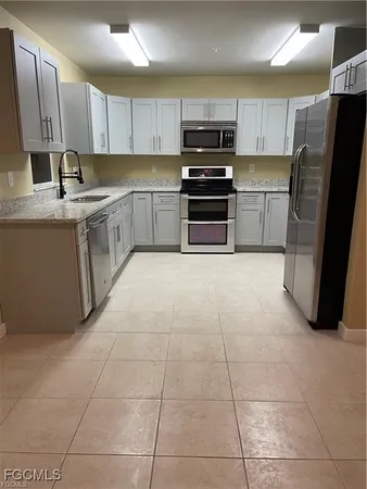 a large kitchen with stainless steel appliances kitchen island granite countertop a sink refrigerator and cabinets