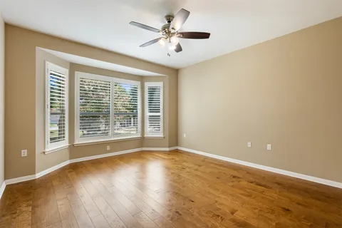 a view of an empty room with window and chandelier fan