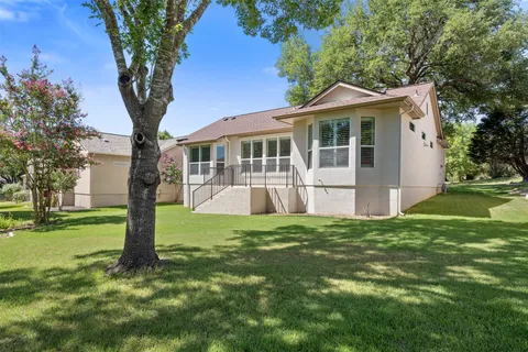 a view of a house with a big yard potted plants and large tree