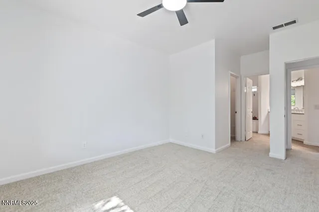 an empty room with a ceiling fan and carpet