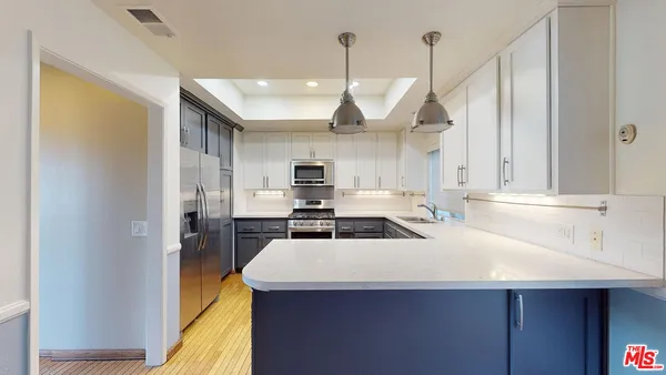 a kitchen with a sink a counter top space stainless steel appliances and cabinets