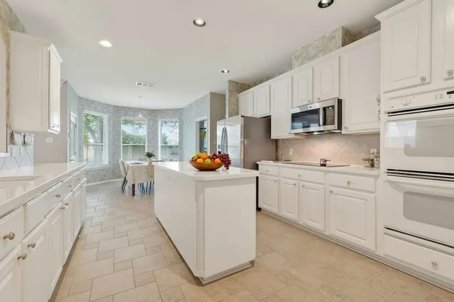 a kitchen with kitchen island granite countertop lots of white stainless steel appliances cabinets and a sink