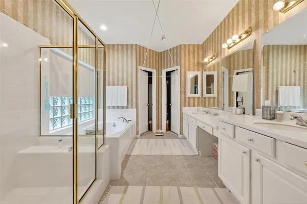 a bathroom with a double vanity sink and mirror with bathtub