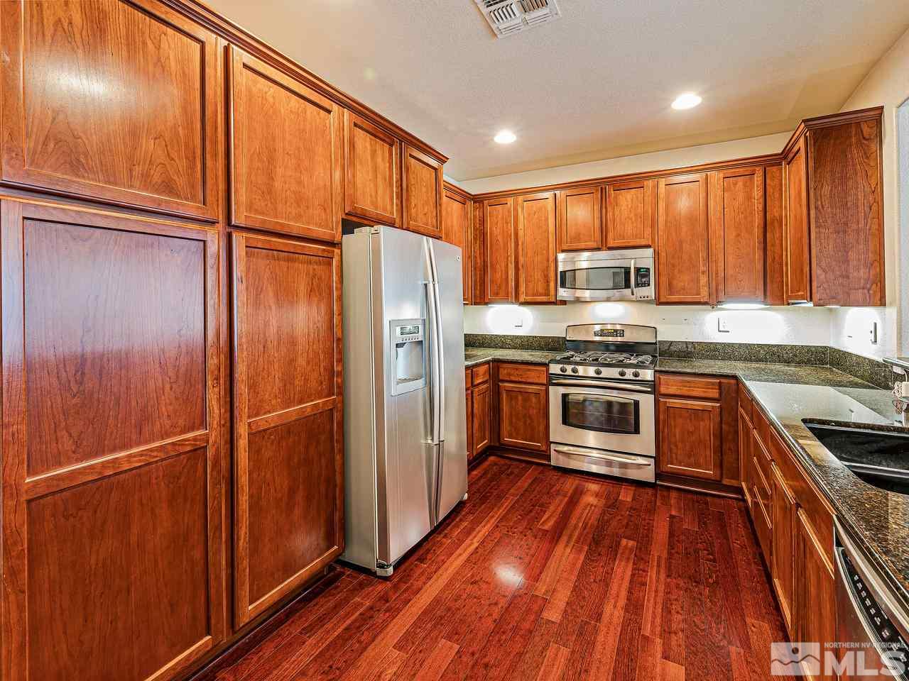 450 Alysheba Court Reno, NV 89521 - Photo 3 of 14 a kitchen with wooden cabinets and stainless steel appliances