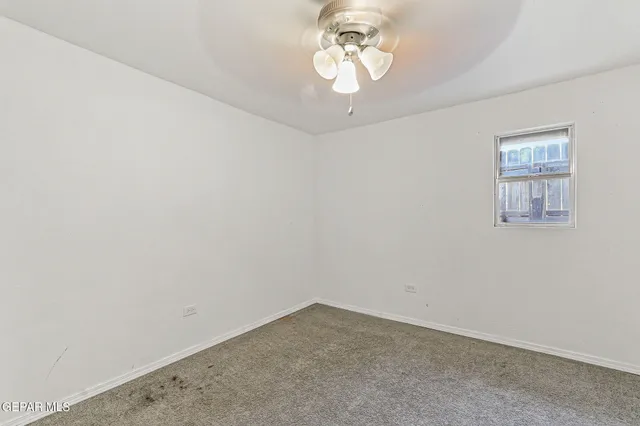 en empty room with a chandelier fan