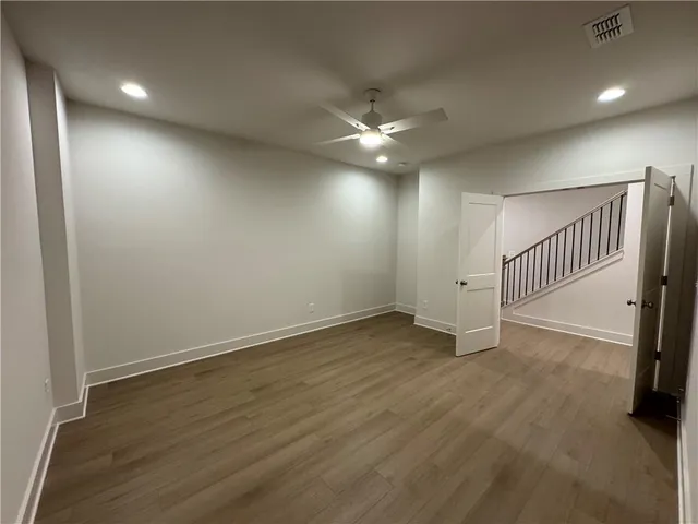 an empty room with wooden floor fan and windows