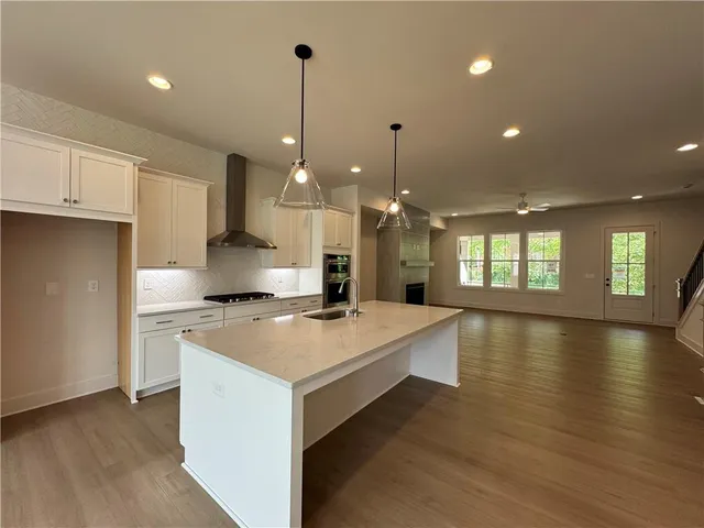 a large kitchen with stainless steel appliances a large counter top a stove and a wooden floors