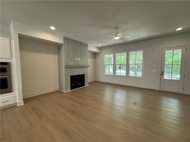 an empty room with wooden floor fireplace and windows