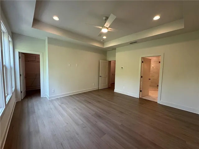 an empty room with wooden floor and a ceiling fan