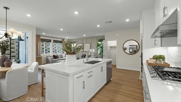 a large white kitchen with a large island stainless steel appliances lots of counter space and a dining table