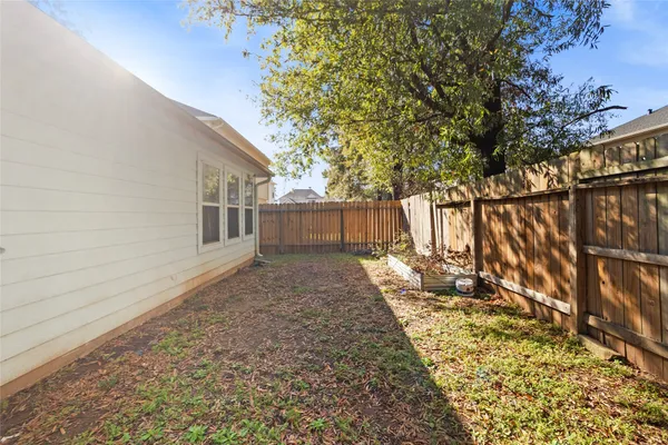 a view of a backyard with wooden fence and large trees