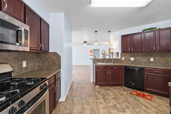 a kitchen with stainless steel appliances granite countertop a stove top oven a sink dishwasher and microwave oven