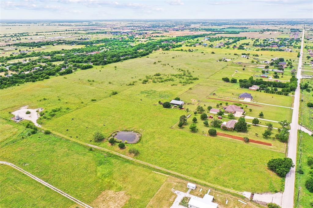 Tbd Florance Road Ponder, TX 76259 - Photo 4 of 8 Expansive green landscape with scattered trees, a visible pond, and a defined roadway