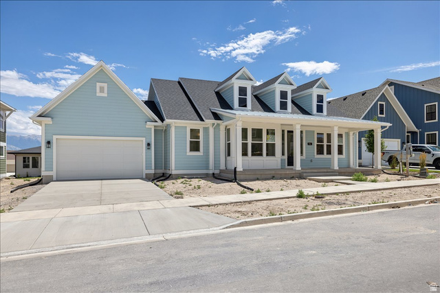 952 Mathilda Drive, Unit 156 Saratoga Springs, UT 84045 - Photo 1 of 25 Light blue siding exterior featuring a covered front porch with white columns, three dormer windows, an attached two-car garage, and a concrete driveway