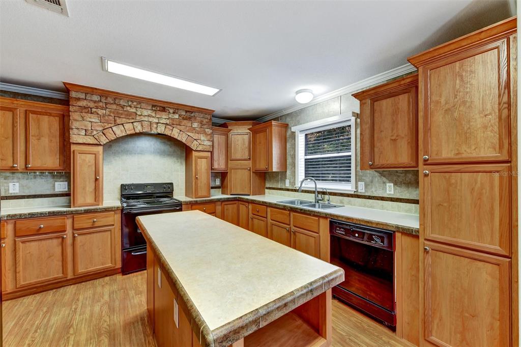 312 Aristides Street Dunedin, FL 34698 - Photo 11 of 38 a kitchen with stainless steel appliances granite countertop a refrigerator a stove a sink dishwasher and white cabinets with wooden floor